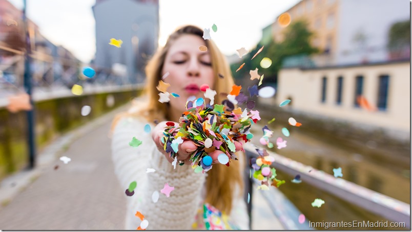 CLose up on the hand of a caucasian blonde woman blowing carnival confetti hand hold - canrival, party, colorful concept